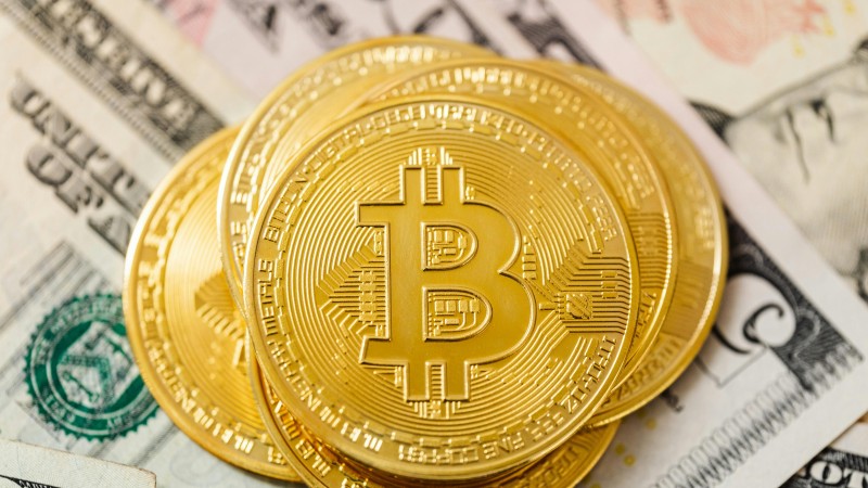 Detailed view of golden Bitcoin coins atop US dollar bills, symbolizing cryptocurrency investment., tags: crypto - pexel