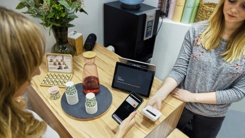 A woman makes a contactless payment at a stylish Berlin café, emphasizing technology and modern retail., tags: india's digital money - pexel