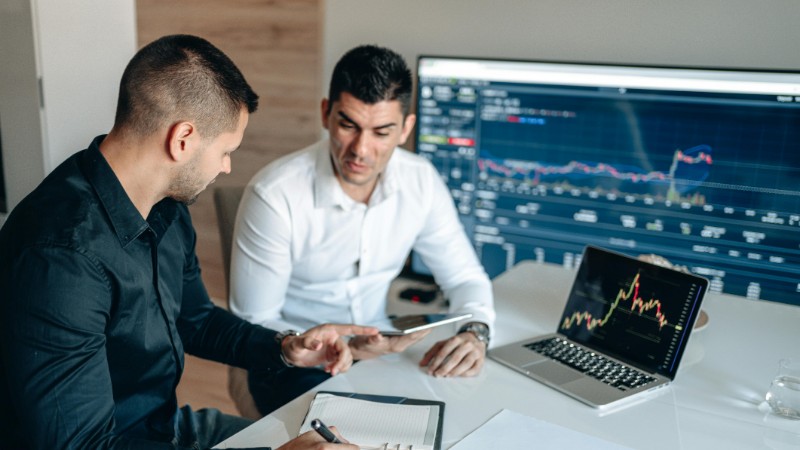 Two businessmen analyzing financial data on digital screens during a collaborative meeting., tags: early-stage - pexel