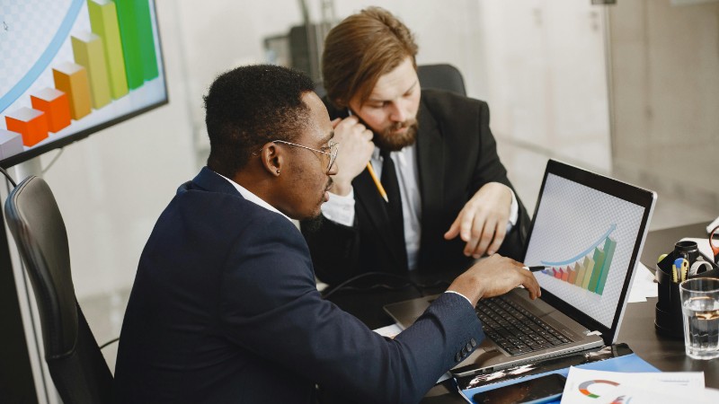 Two business professionals working on growth charts using laptop in an office setting., tags: financial - pexel