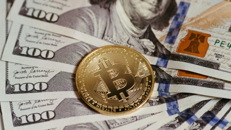Gold Bitcoin coin resting on US dollar bills showcasing digital and traditional currency., tags: quarterly - pexel