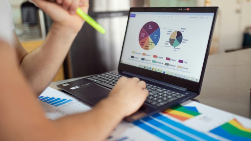 Person analyzing financial charts and graphs on a laptop with colorful documents, showcasing market analysis., tags: markets cautiously confident 2026 - pexel