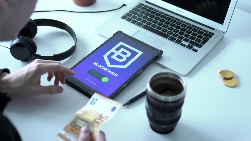 Close-up of digital currency transaction using blockchain technology on tablet with laptop and euro bills., tags: banks cross-border - pexel