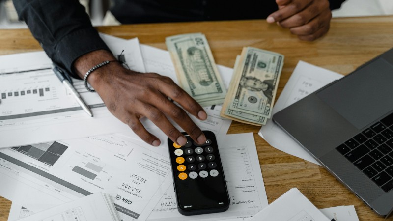 Overhead view of financial documents with calculator, cash, and laptop for financial planning., tags: stability - pexel